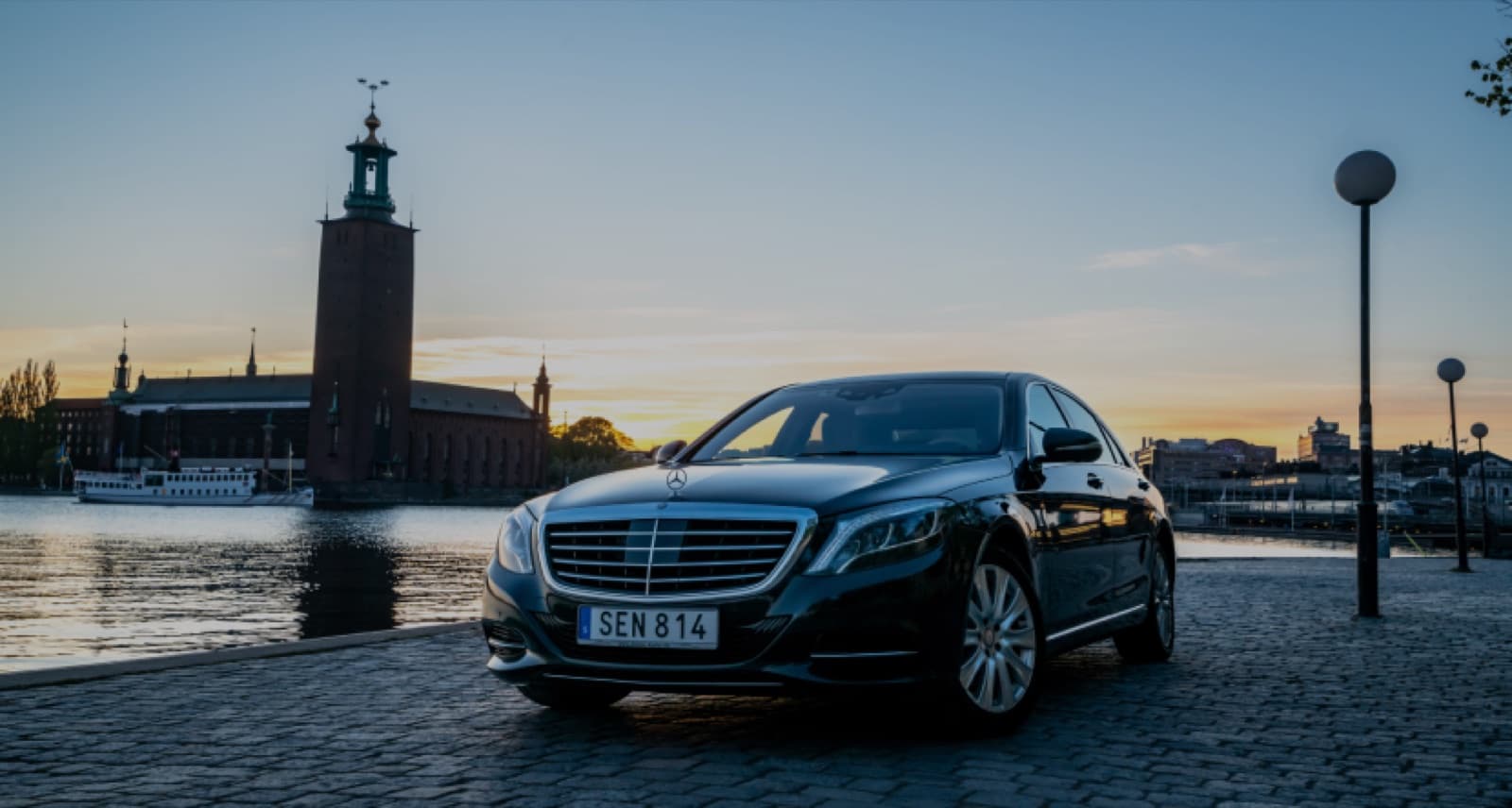 En Mercedes S-Class som väntar vid Stockholms stadshus i solnedgången.